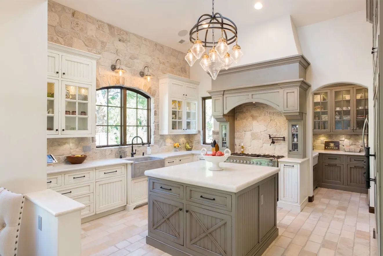 Kitchen with island, arched window, stone hood and chandelier