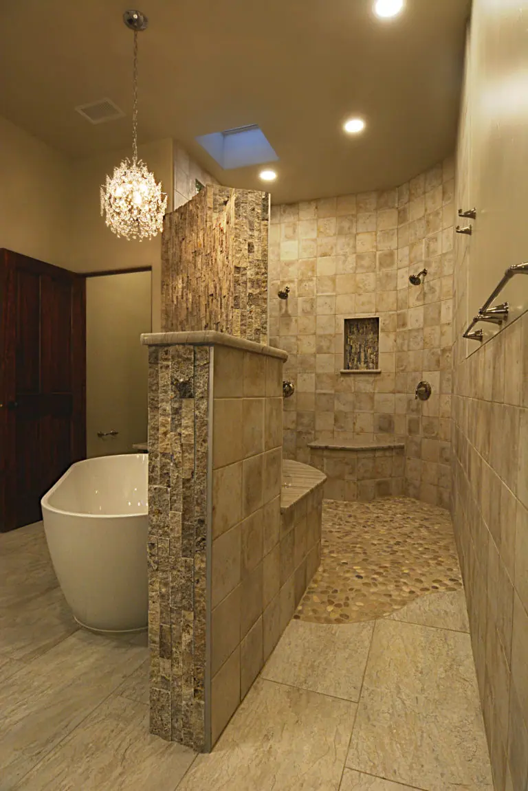 Walk-in stone shower with pebble floor and freestanding tub
