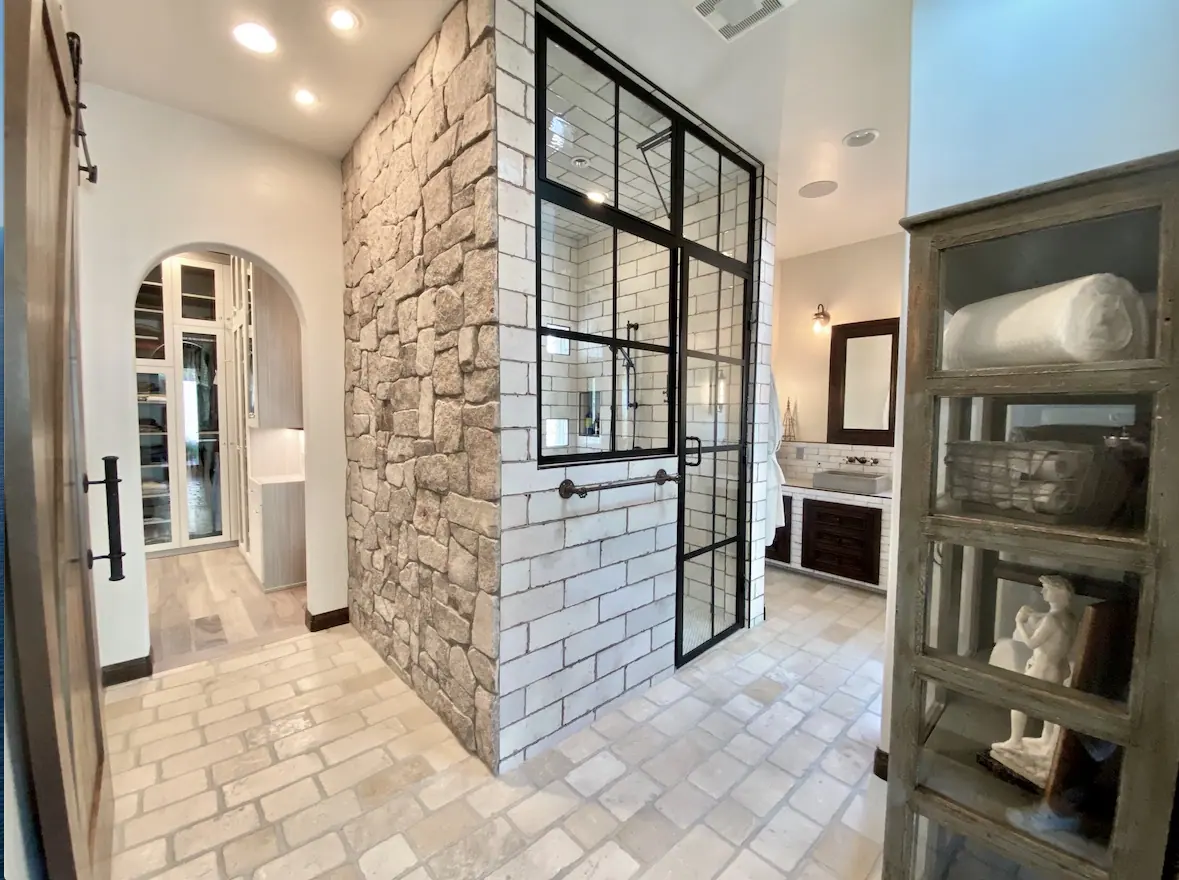 Stone wall, steel-framed shower and archway to closet