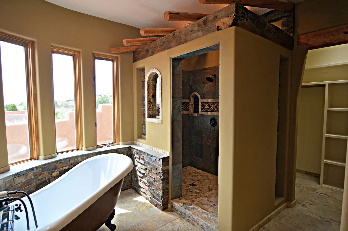 Bathroom with clawfoot tub, stone-faced shower and beamed ceiling