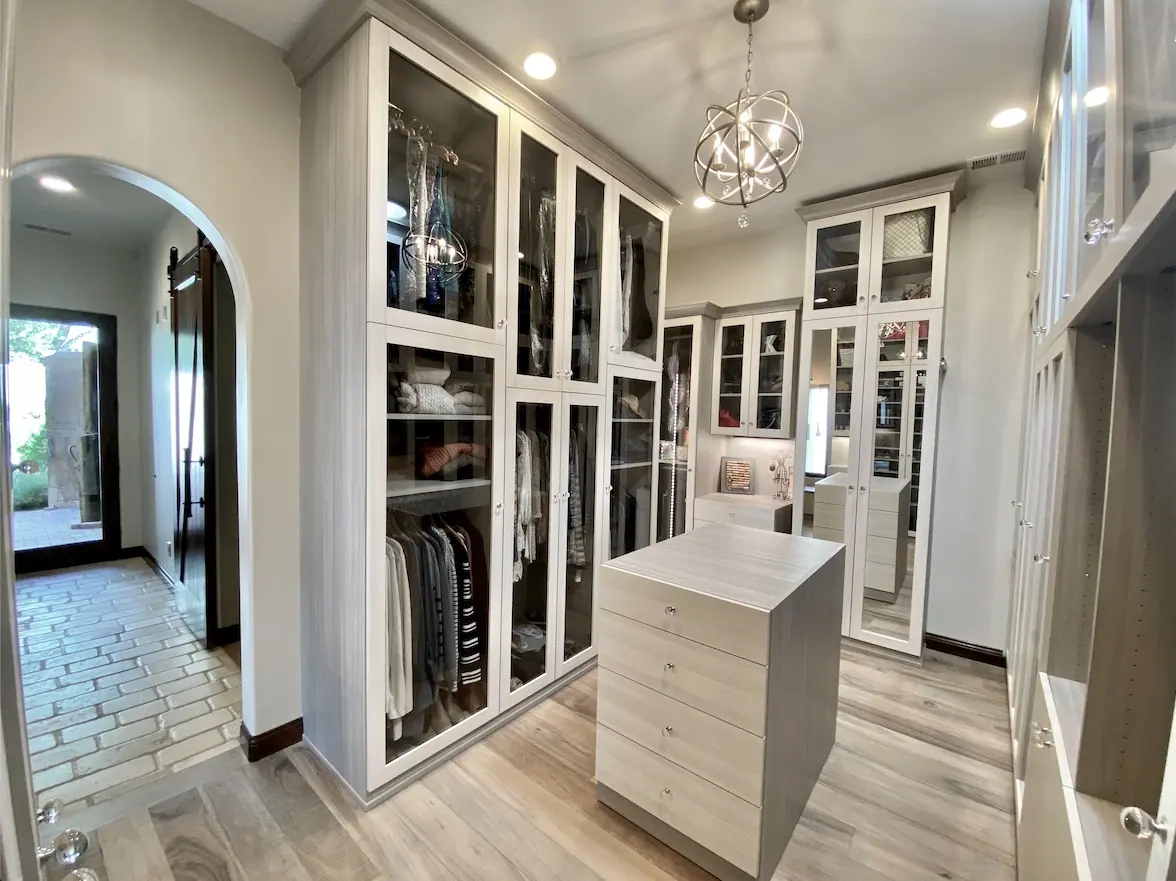 Walk-in closet with glass-front cabinets and island