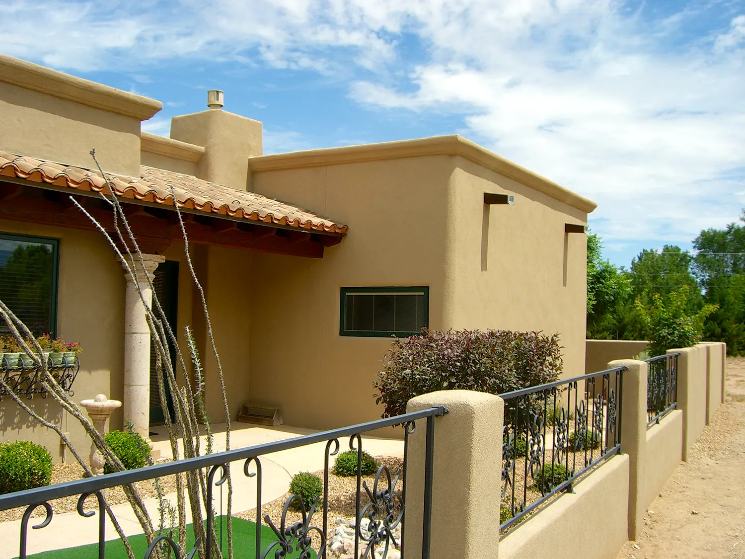Stucco house with tile roof, courtyard wall and iron railing
