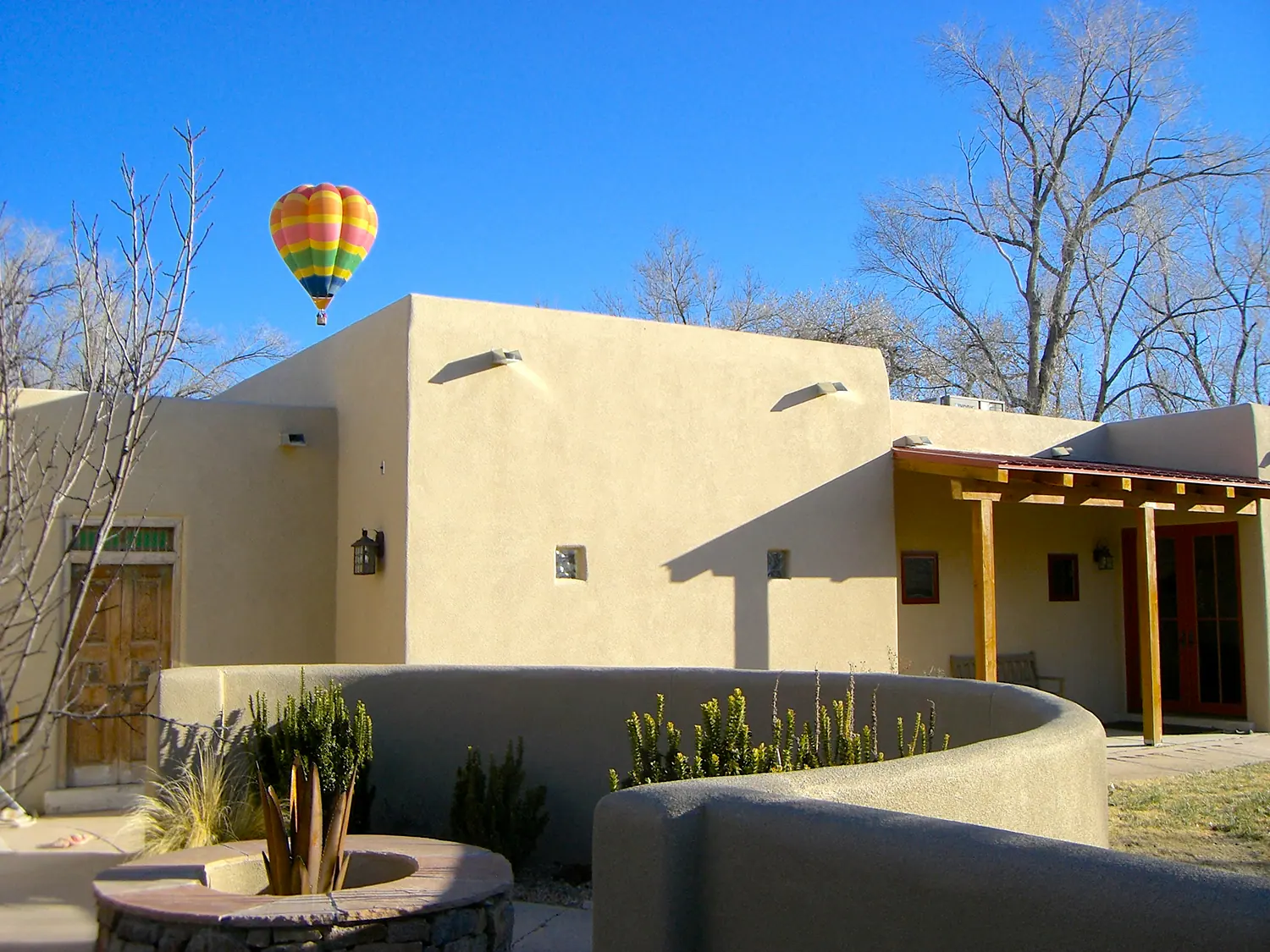 Adobe-style house with curved wall, fire pit and portal